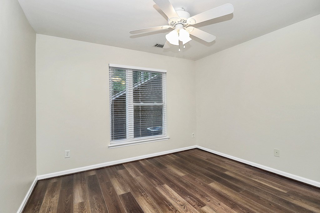 A room with a ceiling fan and wooden flooring.