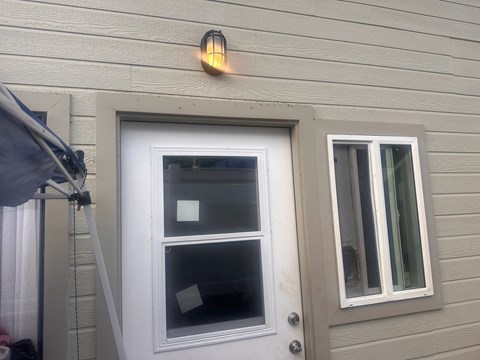 A white door with a window above it and a small light on the wall.