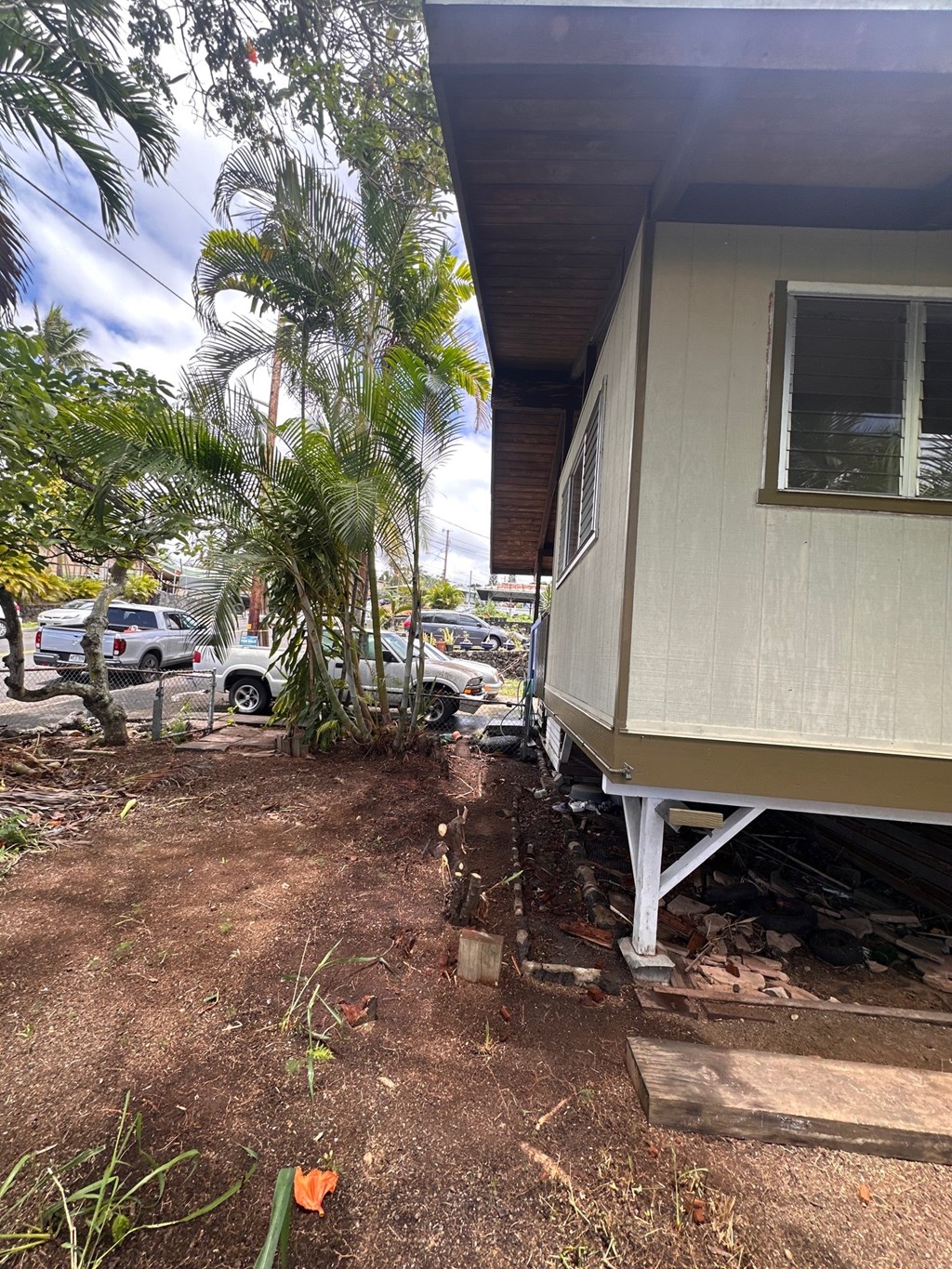A white house with a brown roof and a white car parked in front of it.