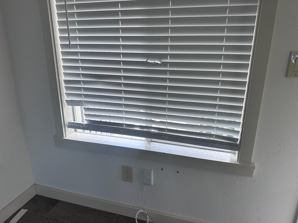 A window with white blinds in a room.