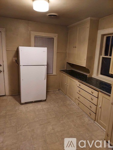 A kitchen with a white fridge and beige cabinets.