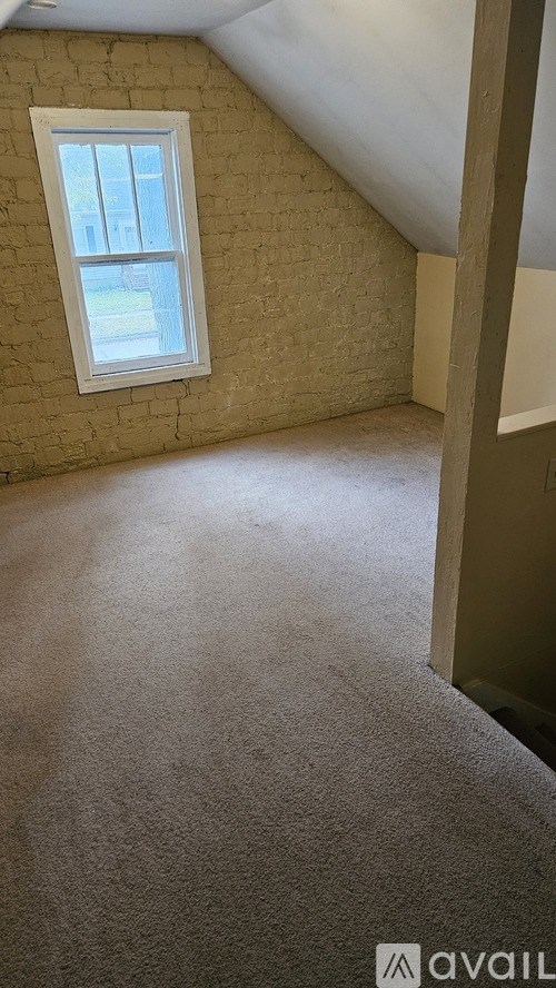 A room with a window and carpeted floor.