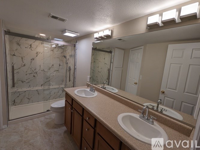 A bathroom with marble tiles and a glass shower stall.