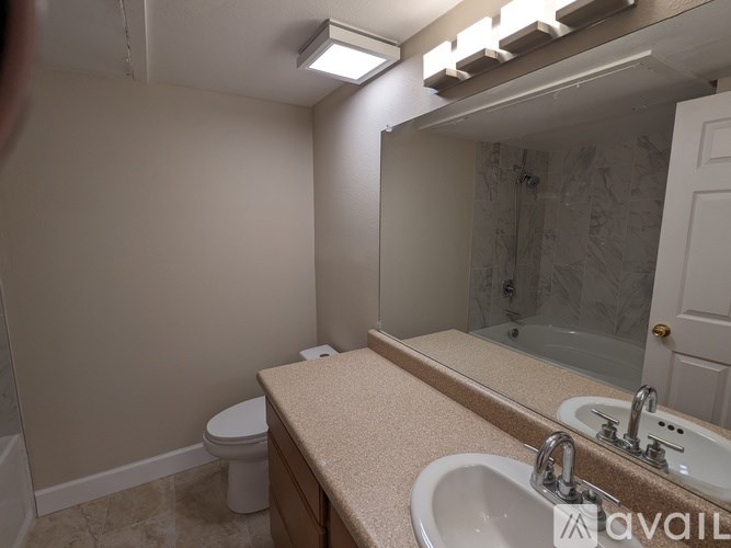 A bathroom with a toilet, sink, and mirror.