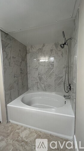 A white bathtub in a bathroom with grey tiles.