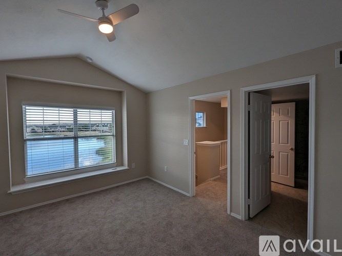A room with a ceiling fan and a window overlooking a body of water.