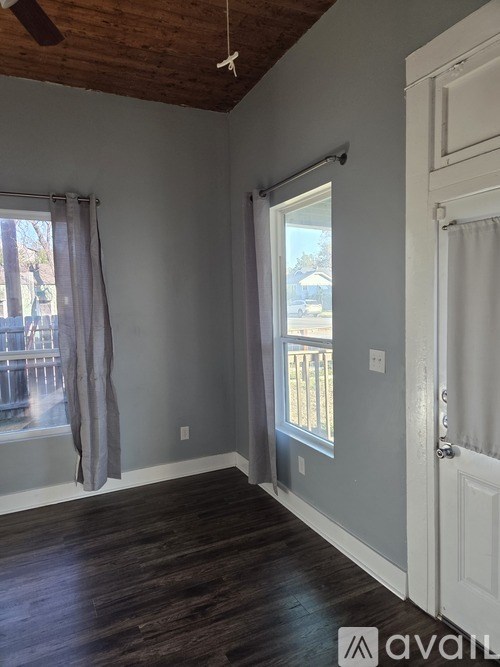 A bedroom with a bed, chair, and window with curtains.