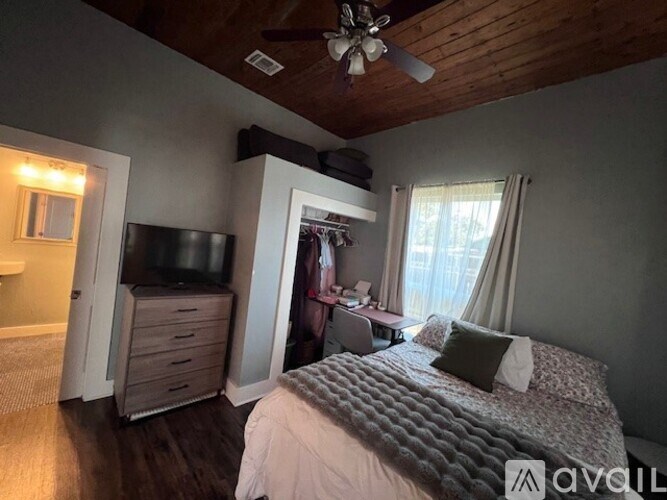 A bedroom with a bed, dresser, and a ceiling fan.