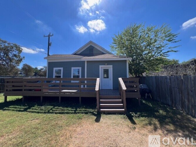 A small house with a porch and a fence in front.