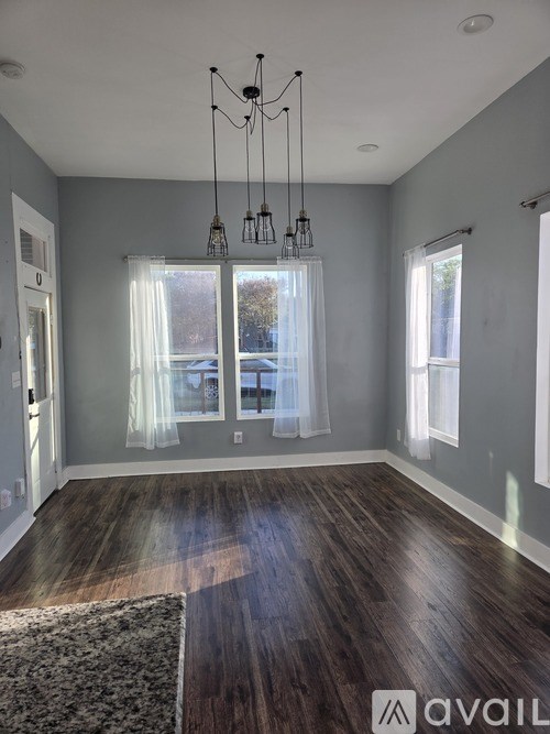 A small house with a porch is surrounded by a wooden fence.