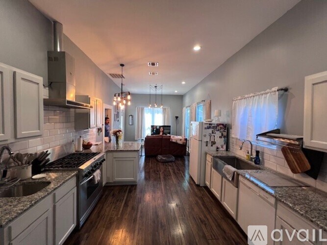 A modern kitchen with wooden floors and white cabinets.