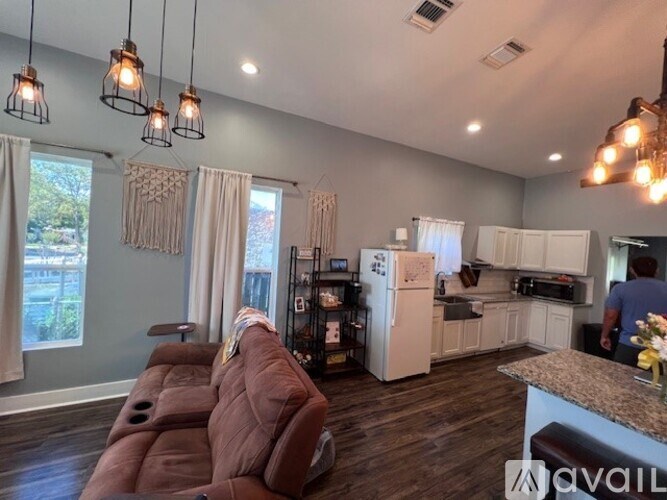 A kitchen with a refrigerator, oven, and a man standing in the background.