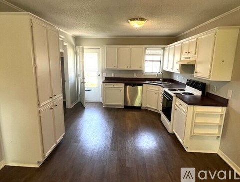 A kitchen with white cabinets and a wooden floor.