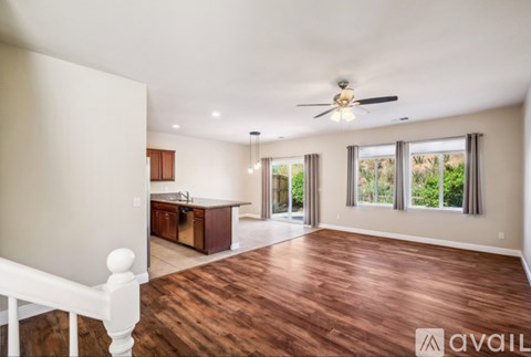 A spacious living room with hardwood floors and a ceiling fan.