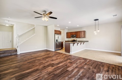 A spacious room with wooden flooring and a ceiling fan.