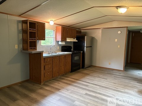 A kitchen with wooden cabinets and a black refrigerator.