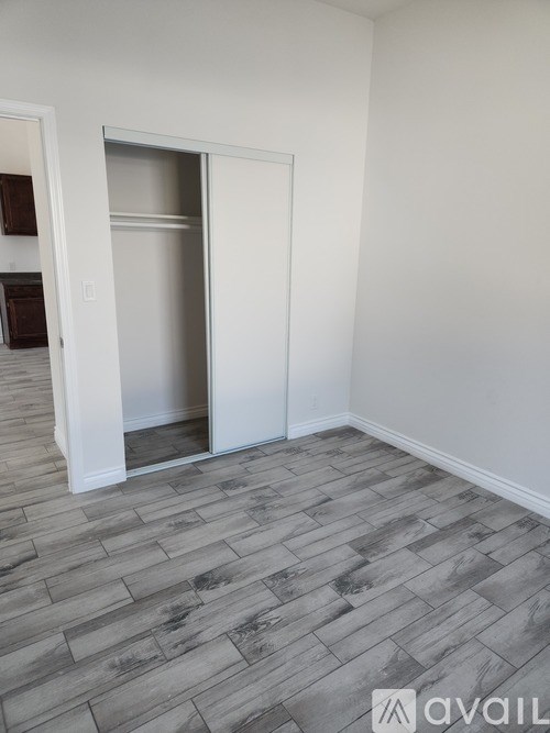 A room with a grey floor and a white wall with a doorway.