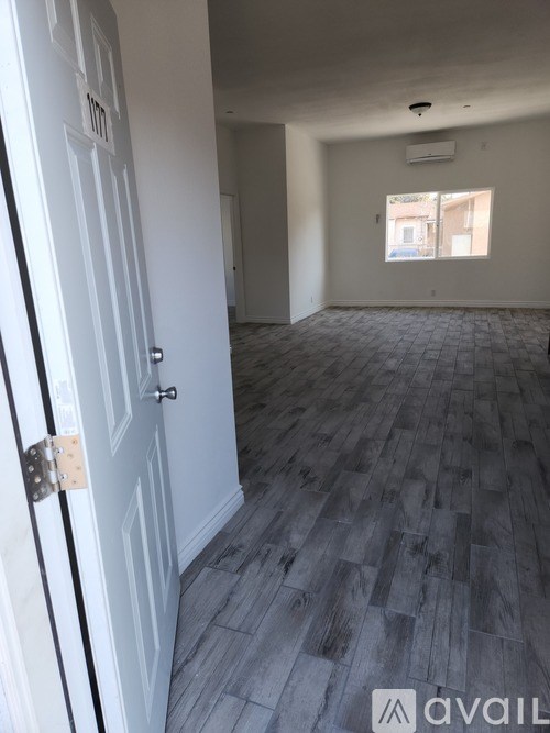 A room with a white door and a window with a view of a building outside.