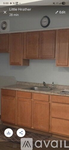 A kitchen with wooden cabinets and a clock on the wall.