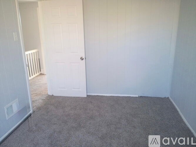 A carpeted room with a door and a wall heater.