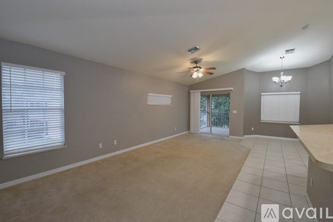A spacious room with a ceiling fan and sliding glass doors.