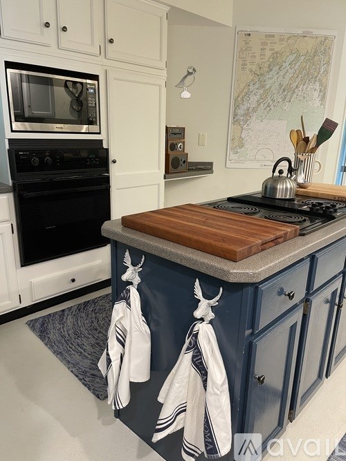 A kitchen with a black stove top and blue cabinets.
