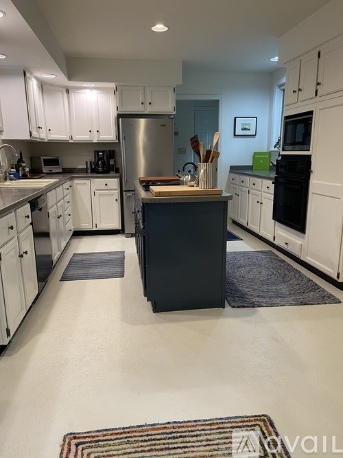 A kitchen with white cabinets and a black island.