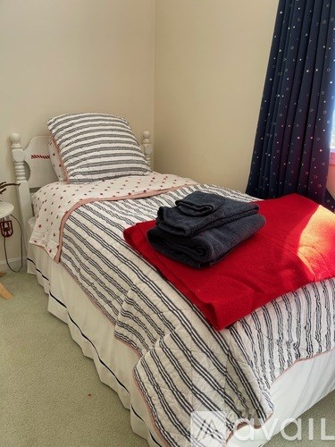 A bed with a striped comforter and a red pillowcase.