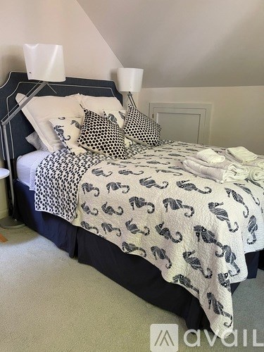A bed with a black headboard and a white and black animal print comforter.