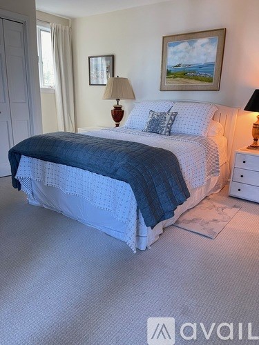 A bedroom with a bed, two lamps, and two pictures on the wall.