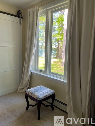 A window with curtains and a small stool in front of it.