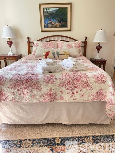 A bed with a floral comforter and a stack of folded towels on top.