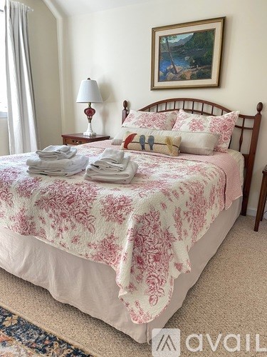 A bed with a red and white bedspread and a painting on the wall.