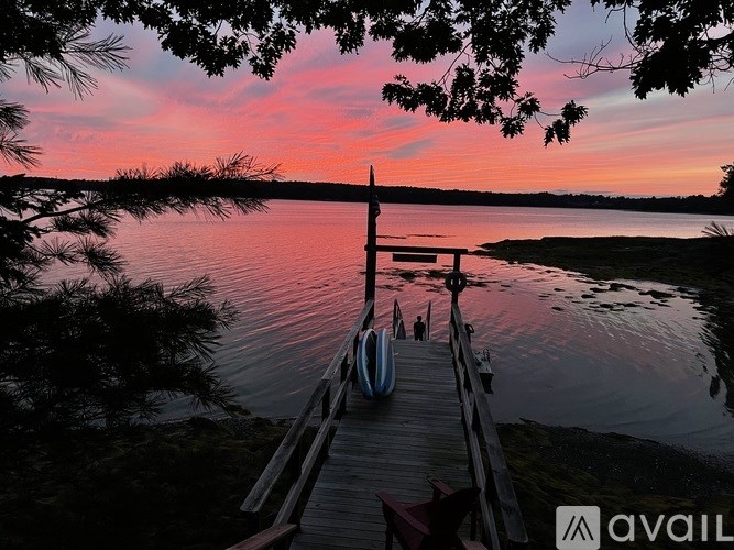 A dock with a bench and a canoe on it during sunset.