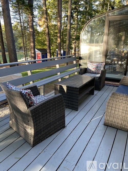 A wooden deck with two wicker chairs and a bench.