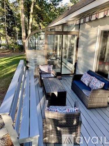 A patio with a couch, chairs, and a table with a glass wall.