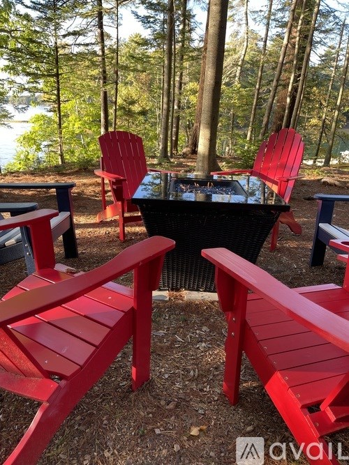 A red table and chairs set up in a wooded area.