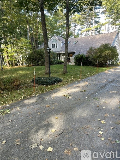 A house is surrounded by trees and a driveway leads to the front door.