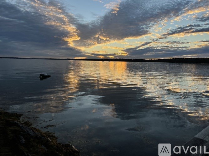 A boat is floating on a calm lake at sunset.
