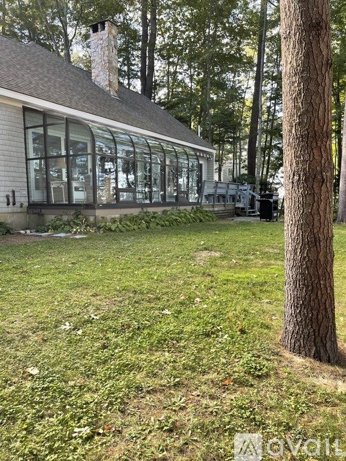A house with a large glass wall is surrounded by trees.