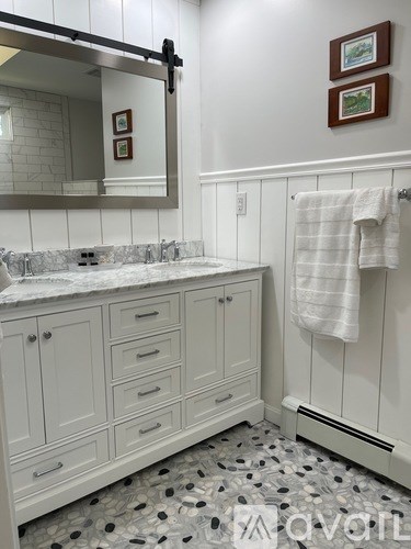 A bathroom with a marble counter top and white cabinets.