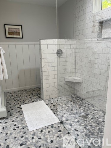 A bathroom with a white tile floor and a white shower stall.