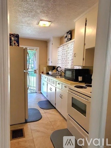 A kitchen with a refrigerator, microwave, and oven.