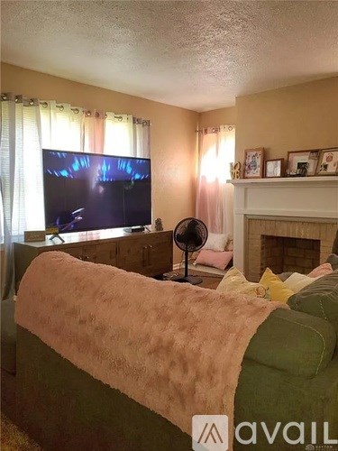 A living room with a green couch and a television on the wall.