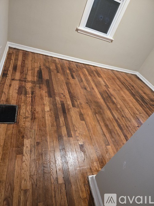 A room with wooden flooring and a window.