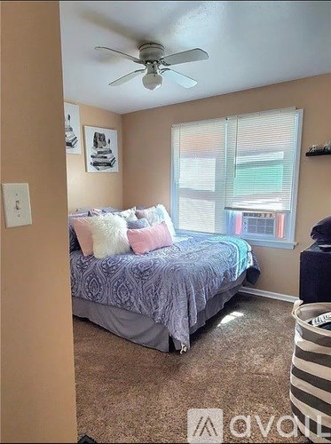 A bedroom with a bed, a ceiling fan, and a window with blinds.