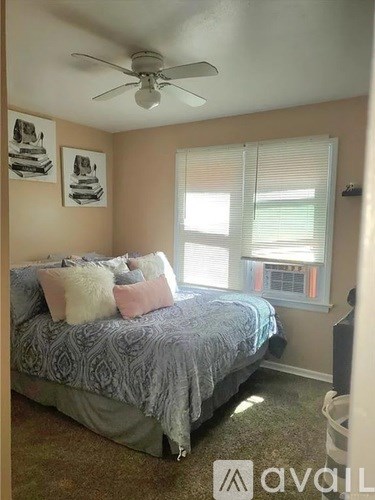 A bedroom with a bed, a ceiling fan, and two pictures on the wall.