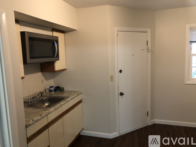 A kitchen area with a microwave, sink, and cabinets.