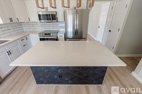 A kitchen with white cabinets and a large island in the middle.