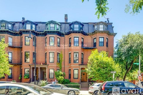 A row of red brick townhouses with green trees in front.